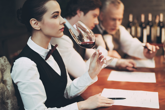 Experienced sommelier woman explores taste of wine in restaurant. Wine tasting. Checking taste, color, sediments of wine.