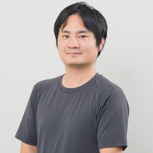 話を聞いた男性のポートレート、グレーのTシャツ姿で正面を向く